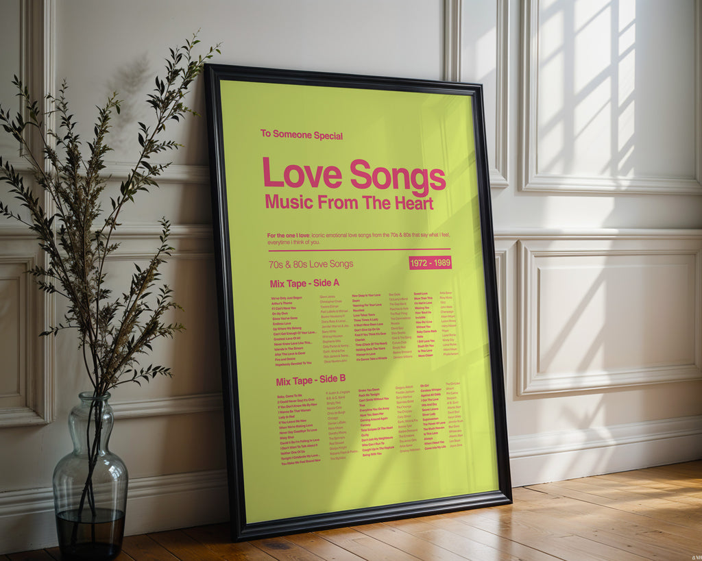 Framed print titled 'Love Songs Music From The Heart' on a wall with a vase and plant.