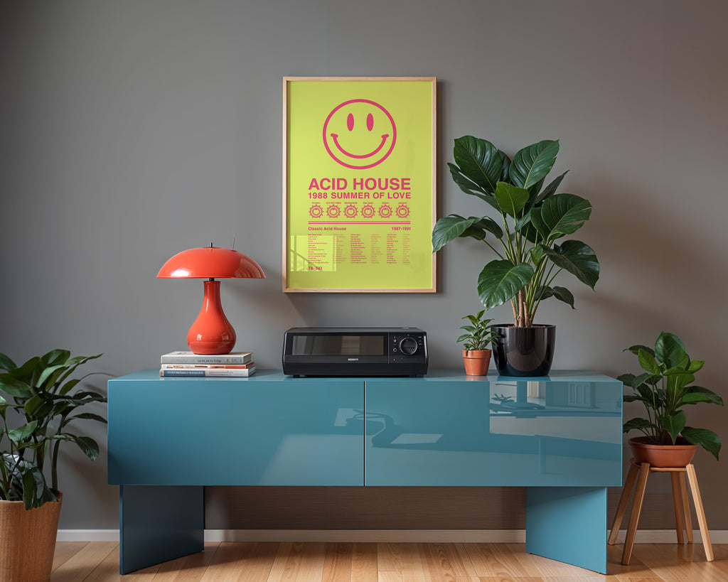 Acid House Smiley Face music print hanging in a black frame on a light grey wall above a modern blue sideboard, with soft window reflections visible on the frame glass. Suitable for A1, A2 and A3 sizes. Acid yellow background with electric pink text (Mockup M06).