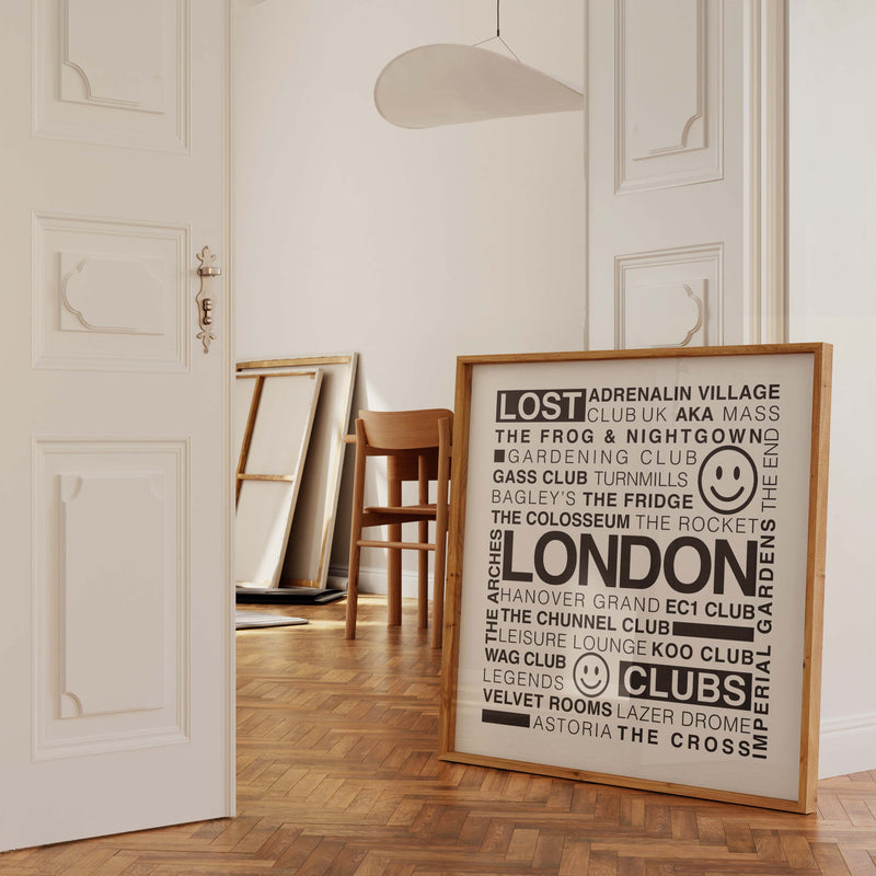 Lost London Clubs square print with black text on white background in a wooden frame leaning against a white ornate wall in a doorway.