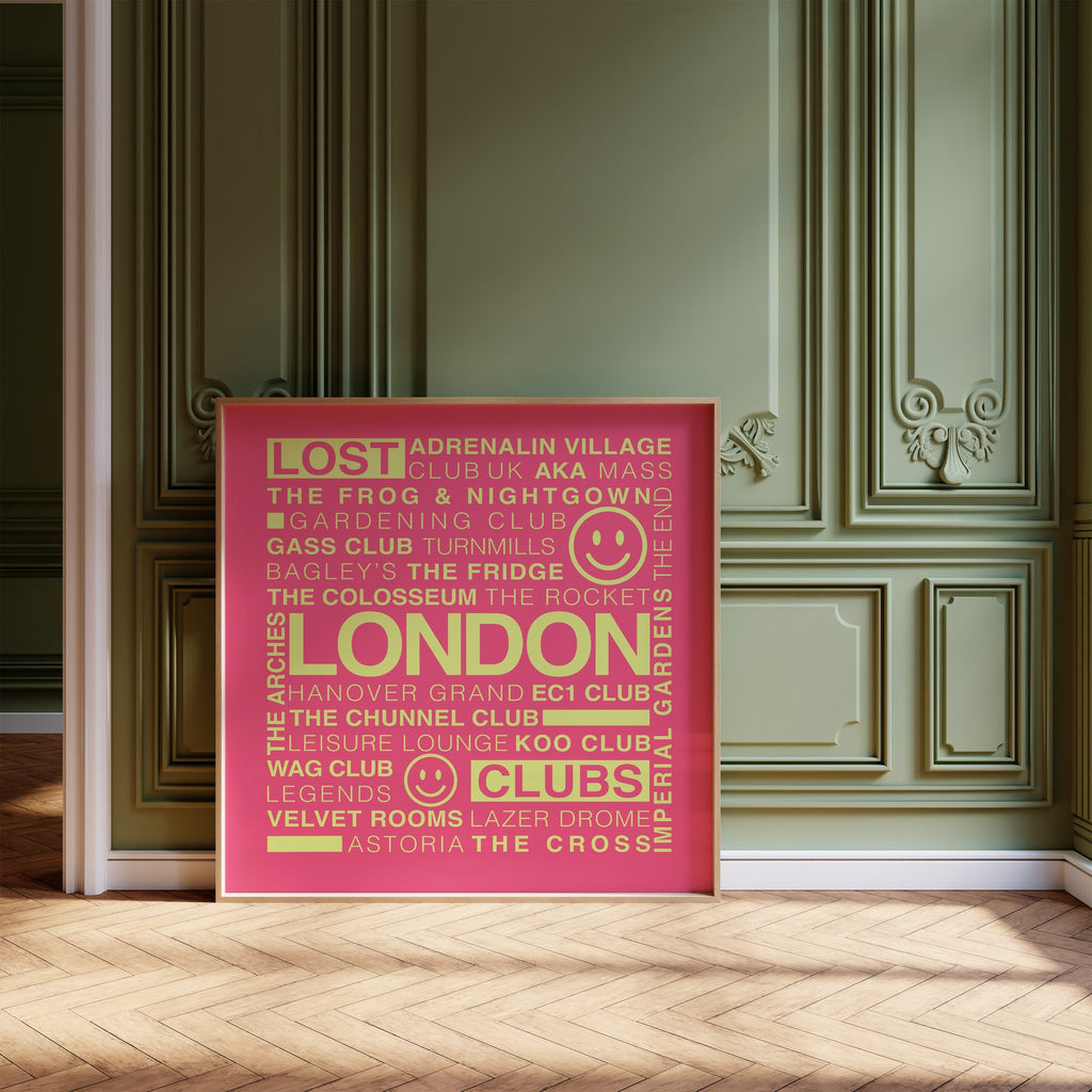 Lost London Clubs square print with electric pink background and acid yellow text in a wooden frame leaning on a wood floor against an olive ornate wall